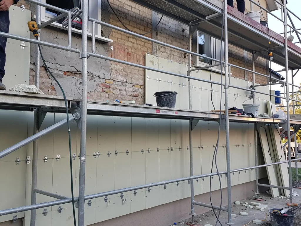 Panneaux isolants fixés sur un mur extérieur depuis un échafaudage